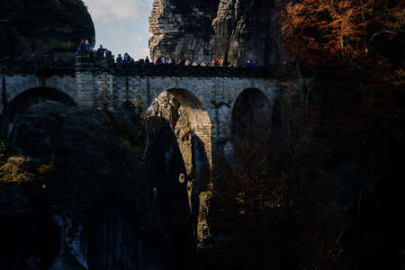 Saxon Switzerland National Park, Germany, 6 November 2021: Bastion Bastei Bridge, Rock Formations in Elbe River Valley, Sandstone Mountains Path, autumn forest landscape at sunny day, rocky valleyのeditorial素材
