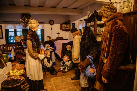 Prerov nad Labem, Czech Republic, 5 December 2021: Interior of traditional regional house, woman greets guests, family gathered around table, Christmas in Skanzen, Polabi open-air ethnographic museumのeditorial素材