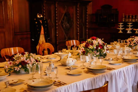 Libochovice, Bohemia, Czech Republic, 19 September 2021: Castle interior with baroque wooden furniture, dining room, table with porcelain and crystal glasses, cupboard for plates, vases with flowersのeditorial素材