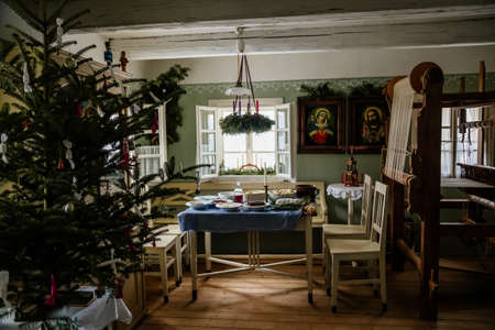 Kourim, Czech Republic, 26 December 2021: Interior of Traditional village house, set table with candles, icons, Christmas tree in Skanzen, country-style architecture, open-air ethnographic museumのeditorial素材