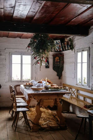 Kourim, Czech Republic, 26 December 2021: Interior of Traditional village house, benches and table, tree upside down, country-style architecture, Christmas in Skanzen, open-air ethnographic museumのeditorial素材