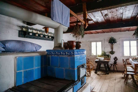 Kourim, Bohemia, Czech Republic, 26 December 2021: Interior of Traditional village house, blue ceramic tiled stove, table and chairs, country-style architecture, open-air ethnographic museumのeditorial素材