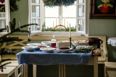 Kourim, Czech Republic, 26 December 2021: Interior of Traditional village house, set table with candles, icons, Christmas tree in Skanzen, country-style architecture, open-air ethnographic museumのeditorial素材