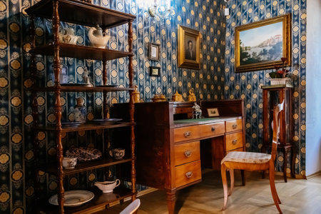 Kolin, Czech Republic, 26 December 2021: Regional Museum Town House Cervinkovsky dum, Interior with Biedermeier style furniture, desk or writing table, rack with chinaware, paintings in gilded framesのeditorial素材