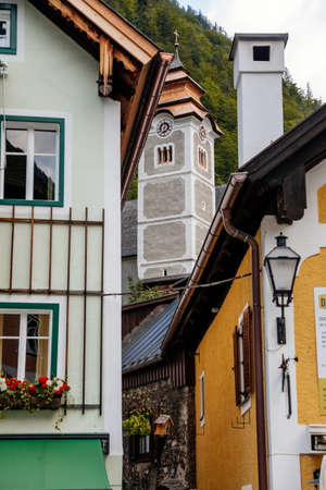 Hallstatt, Austria, 27 August 2021: Colorful scenic picturesque town street at summer day, mountain village near lake, Alps, Catholic church Parish Of Assumption, UNESCO heritage, traditional housesのeditorial素材