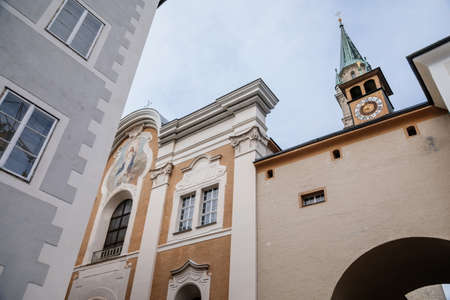 Salzburg, Austria, 28 August 2021: arch with religious fresco and small bell tower with clock at...