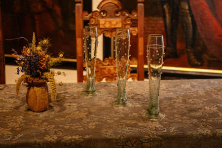 Karlstejn, Bohemia, Czech Republic, 12 March 2022: historical replica of forest medieval historical wine glass on table, medieval gothic castle interior, antique wood carved furniture, dining roomのeditorial素材