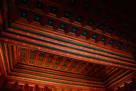 Karlstejn, Czech Republic, 12 March 2022: medieval gothic castle interior, antique wood carved furniture, wooden cassette ceiling blue and red, royal audience hall, throne by the windowのeditorial素材
