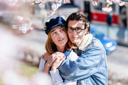 Happy young family lovely couple enjoy walking in spring blooming park, sunny garden on Petrin Hill in Prague, almond and Sakura, close-up portrait, man holds the woman's hand, relationships in loveの写真素材