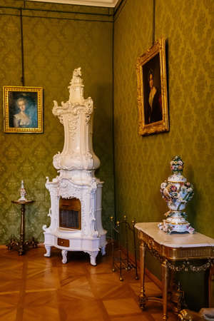 Lazne Kynzvart, Bohemia, Czech Republic, 7 August 2021: Metternich representative chateau or castle interior, baroque and classic furniture, Antique white ceramic tiled stove, Meissen porcelain vaseのeditorial素材