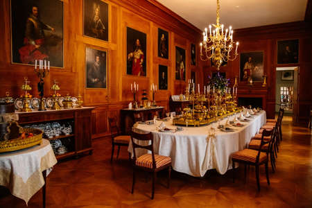 Lazne Kynzvart, Czech Republic, 7 August 2021: Metternich representative chateau or castle interiors, dining room with long table and gilded porcelain dishes, plates and glasses, golden candelabraのeditorial素材