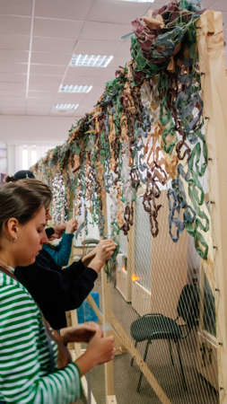 Kyiv, Ukraine, 7 April 2022: Civilian volunteers weave and knit camouflage nets for Ukrainian Military, sewing and craft cover camouflage for army troops, people woman and children mobilize to helpのeditorial素材