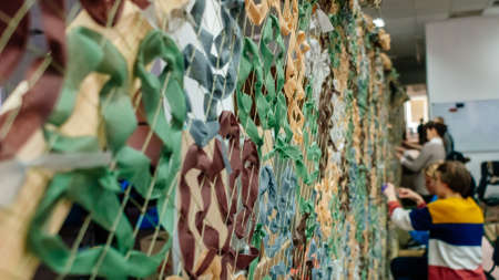 Kyiv, Ukraine, 7 April 2022: Civilian volunteers weave and knit camouflage nets for Ukrainian Military, sewing and craft cover camouflage for army troops, people woman and children mobilize to helpのeditorial素材