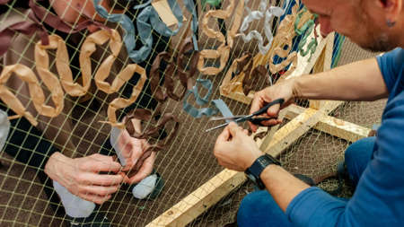 Kyiv, Ukraine, 7 April 2022: Civilian volunteers weave and knit camouflage nets for Ukrainian Military, sewing and craft cover camouflage for army troops, people woman and children mobilize to helpのeditorial素材