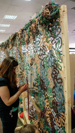 Kyiv, Ukraine, 7 April 2022: Civilian volunteers weave and knit camouflage nets for Ukrainian...