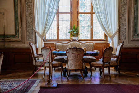 Litomysl, Czech Republic, 17 April 2022: Castle interior, living or dining room with baroque wooden carved furniture, antique sofa and soft armchairs near window, porcelain tea set on tableのeditorial素材