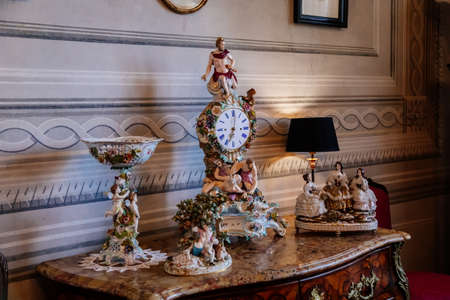 Litomysl, Czech Republic, 17 April 2022: castle chateau baroque representative interior with baroque classic furniture, Meissen porcelain, figurines clocks stand on carved wooden chest of drawersのeditorial素材