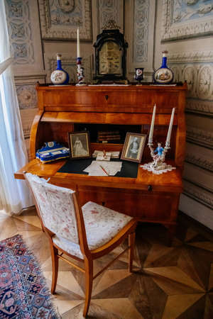 Litomysl, Czech Republic, 17 April 2022: castle chateau representative interior with baroque classic furniture, wooden writing desk and chair near windows, Photos, figurines and documentsのeditorial素材