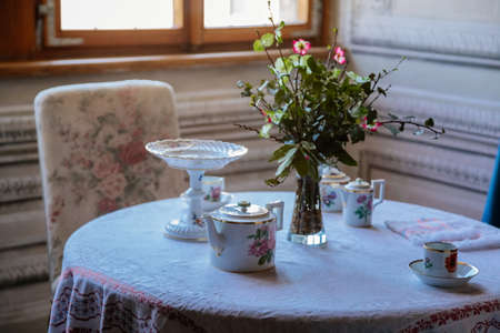 Litomysl, Czech Republic, 17 April 2022: Castle interior, living or dining room with baroque wooden carved furniture, antique sofa and soft armchairs near window, porcelain tea set on tableのeditorial素材