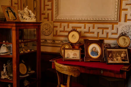 Litomysl, Czech Republic, 17 April 2022: castle chateau baroque representative interior with baroque classic furniture, vintage framed photographs on the table, porcelain figurinesのeditorial素材