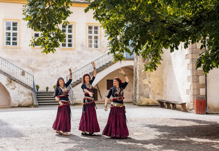 Krivoklat, Czech Republic, 21 August 2022: Courtyard of fortified medieval royal gothic castle, cultural landmark in summer day, gypsies in national dress, beautiful girls in long skirts are dancingのeditorial素材