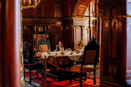 Hradek u nechanic, Czech Republic, 8 October 2022: Castle or chateau interior with wooden carved furniture, dining room with service on the table, wood paneling on the walls, red velvet carpetのeditorial素材