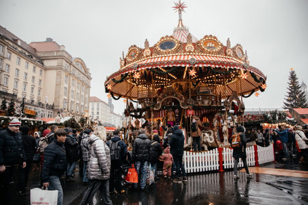 Dresden, Saxony, Germany, 10 December 2022: Christmas outdoor market stall decorations with fairy with lights, vintage french carousel, figures of horses, attraction for tourists, winter day and snowのeditorial素材