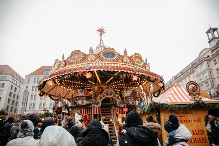Dresden, Saxony, Germany, 10 December 2022: Christmas outdoor market stall decorations with fairy with lights, vintage french carousel, figures of horses, attraction for tourists, winter day and snowのeditorial素材