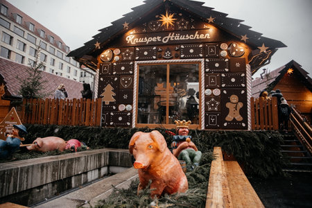 Dresden, Saxony, Germany, 10 December 2022: Christmas outdoor market stall decorations with fairy with lights, painted gingerbread house made, figurine of pig, witch with cat, winter day and snowのeditorial素材