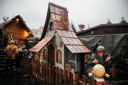 Dresden, Saxony, Germany, 10 December 2022: Christmas outdoor market stall decorations with fairy with lights, painted gingerbread house made, figurine of pig, witch with cat, winter day and snowのeditorial素材
