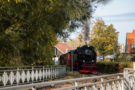 Wernigerode, Germany, 29 October 2022: Steam engine train in Harz Mountains Region, Old retro vintage steam locomotive near railway station at sunny day, white smoke from train chimney, Brocken Lineのeditorial素材