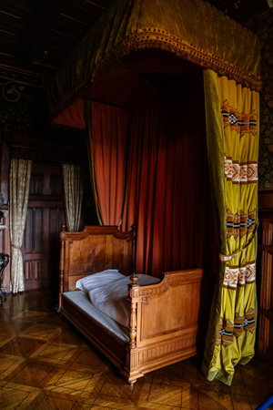 Wernigerode, Saxony-Anhalt, Germany, 29 October 2022: representative chateau or castle interiors, bedroom with a wooden carved antique canopy bed, velvet heavy green curtains, patterned parquetのeditorial素材