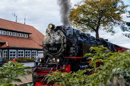 Wernigerode, Germany, 29 October 2022: Steam engine train in Harz Mountains Region, Old retro vintage steam locomotive near railway station at sunny day, white smoke from train chimney, Brocken Lineのeditorial素材