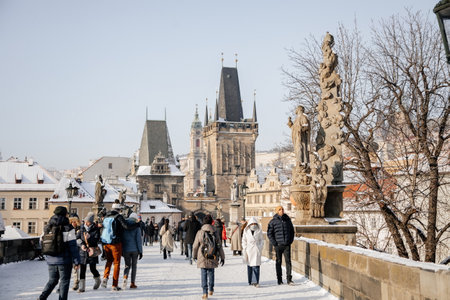 Prague, Czech Republic, 15 December 2022: Lesser Town with Mala Strana bridge towers with spire above River Vltava, View from Charles bridge, snow on sunny winter day, baroque sculptures and lamppostsのeditorial素材