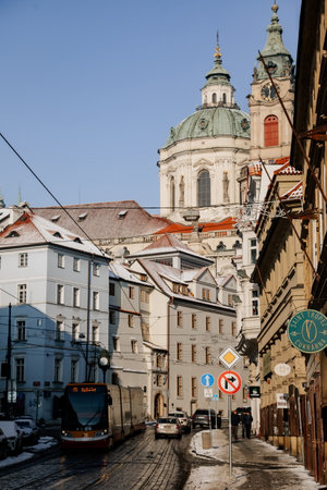 Prague, Czech Republic, 15 December 2022: View of Baroque Church of Saint Nicholas, green dome and bell tower with clock, sunny winter day, snow on red roofs, Mala Strana or Lesser Town districtのeditorial素材