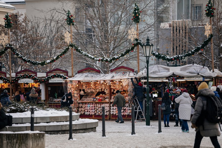Prague, Czech Republic, 19 December 2022: Christmas market under snow with wooden stalls and luminous garlands in Republic Square in old town on sunny winter day, Christmas tree, New Year atmosphereのeditorial素材