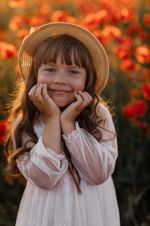 Portrait of cute girl in white dress and straw hat in field with poppies in evening at sunset, happy child, Stylish kid, Summer countryside nature flowers, Female relaxing, Rural simple life, familyの写真素材