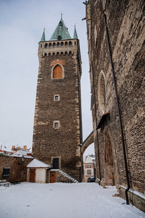 Kolin, Czech Republic, 17 December 2022: Medieval stone St. BartholomewÂ´s Church with tower under snow in winter day, arched windows, chimeras and gargoyles, Gothic Cathedral with belfry, Christmasのeditorial素材