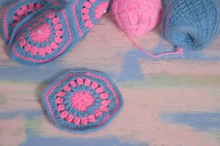 Handmade knitted pink and blue napkin with skeins of yarn on a pink-blue tableの写真素材