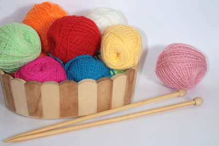 Colorful balls of wool yarn in a decorative basket and wooden knitting needlesの写真素材