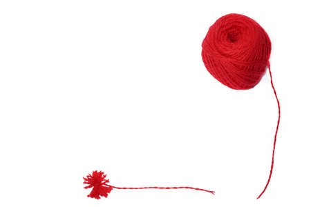 A red ball of wool yarn for knitting and a pompon made of yarn on a white backgroundの写真素材