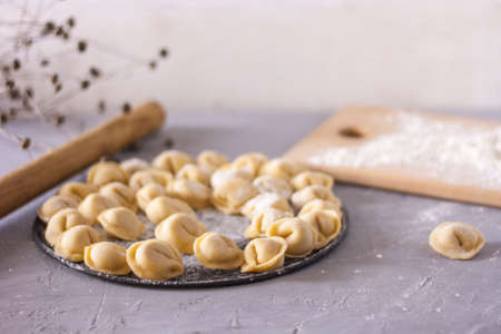 Homemade ravioli on a round platter on the table with flourの写真素材