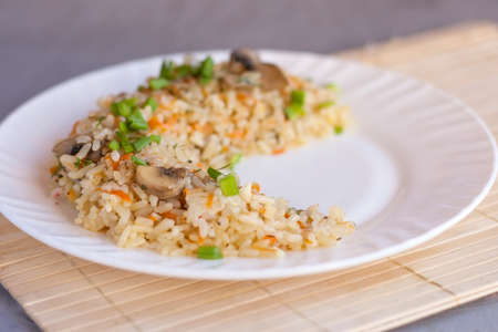 White plate with pilaf. Plov is a traditional tasty dish of roasted meat, onions, carrots, onions and garlic. White plate with pilaf.の写真素材