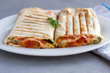 Suluguni in pita bread with greens and tomatoes on a white plate, healthy foodの写真素材