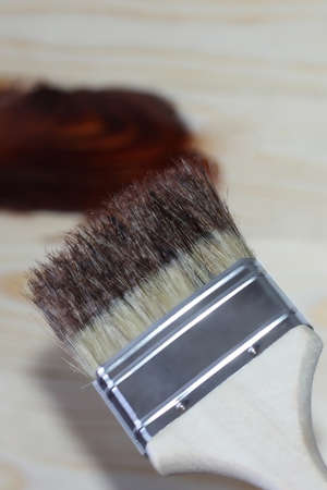 The wide construction brush puts mastic on a light wooden board. The concept of construction and...