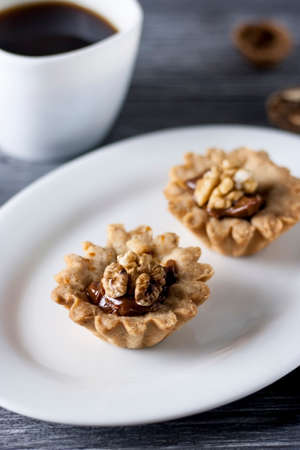 Homemade baking. Shortcake baskets with walnuts and condensed milk and fortune cookies on a white...