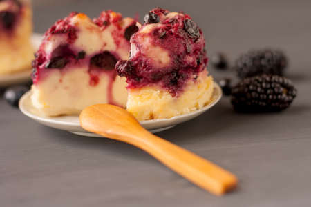 Delicious cottage cheese casserole with berries, cottage cheese pudding with berries. Appetizing fresh cottage cheese casserole with blueberries, raspberries, dewberries and blackberries on a dark background.の写真素材