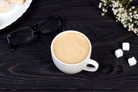 Workplace mockup with a cup of cappuccino coffee on a wooden dark table.の写真素材