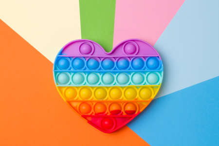 Silicone rainbow heart toy on colorful multicolored background.の写真素材