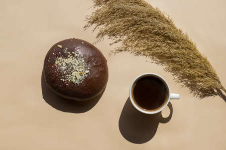 Cup of black coffee with chocolate loaf on a beige background with hard shadows on a bright sunny...